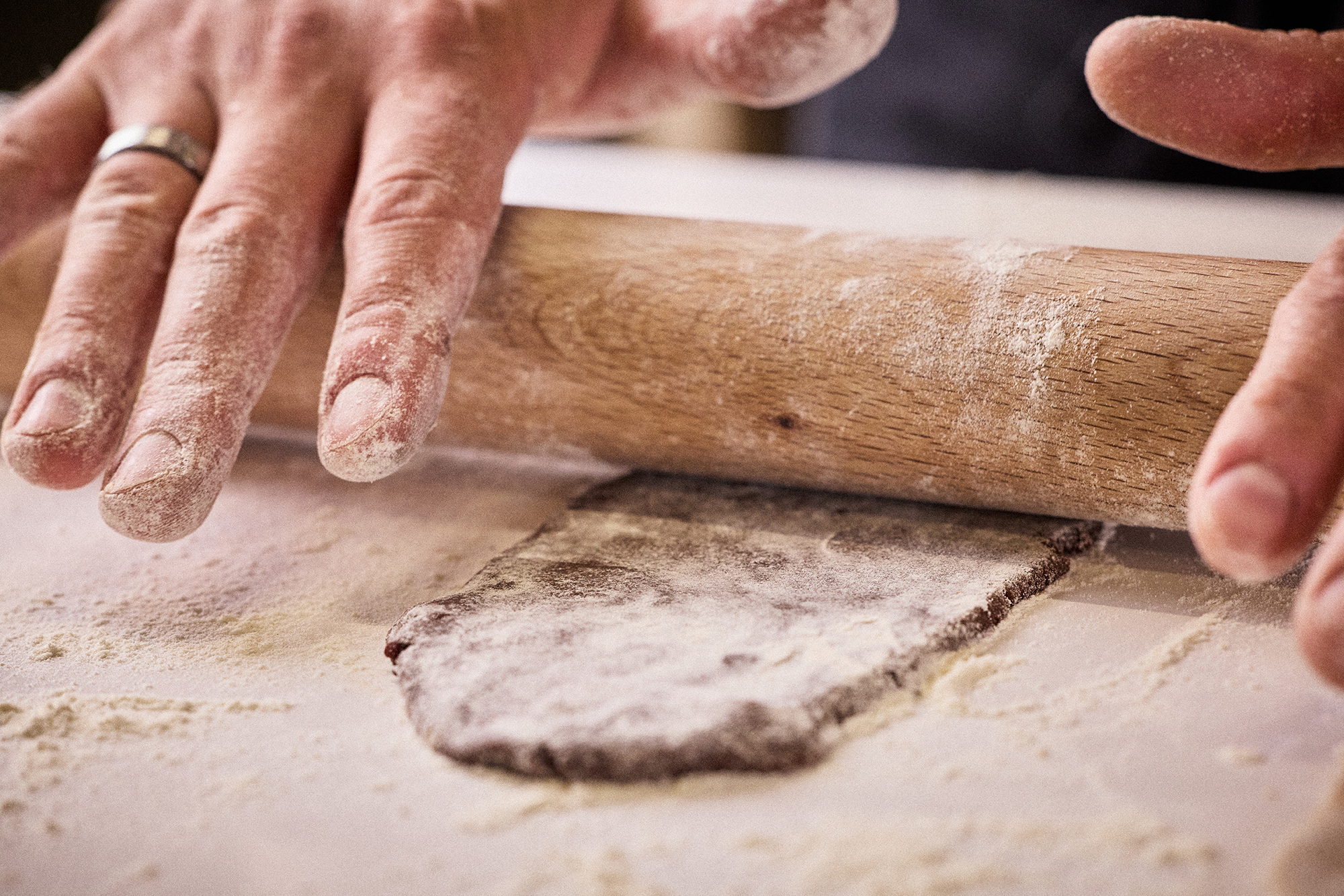 Mains étalant une pâte au rouleau sur un plan de travail fariné