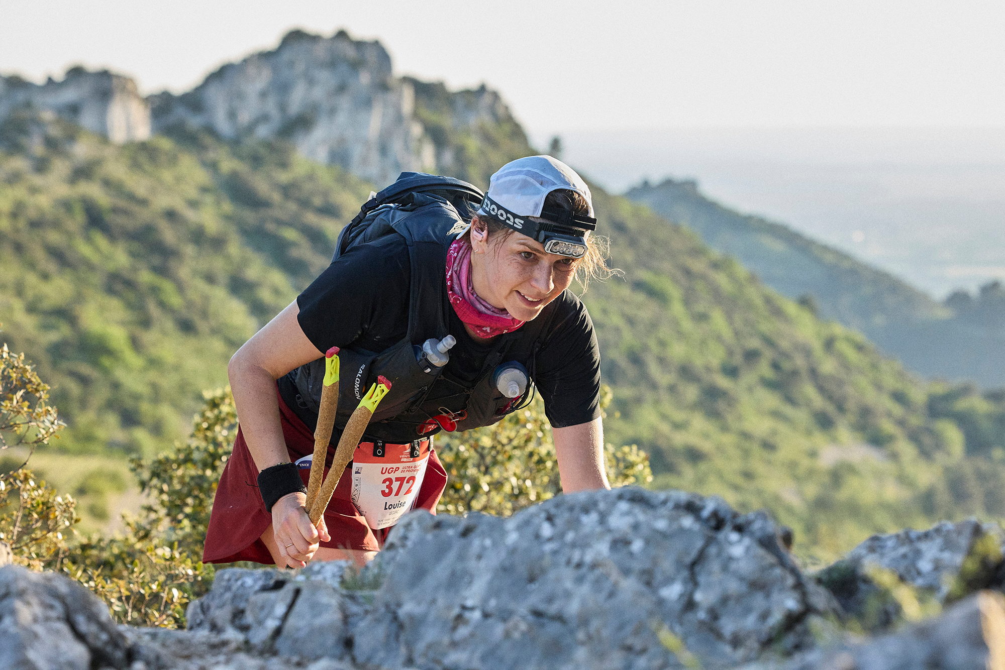 Coureur franchissant un ressaut rocheux, massif en arrière-plan