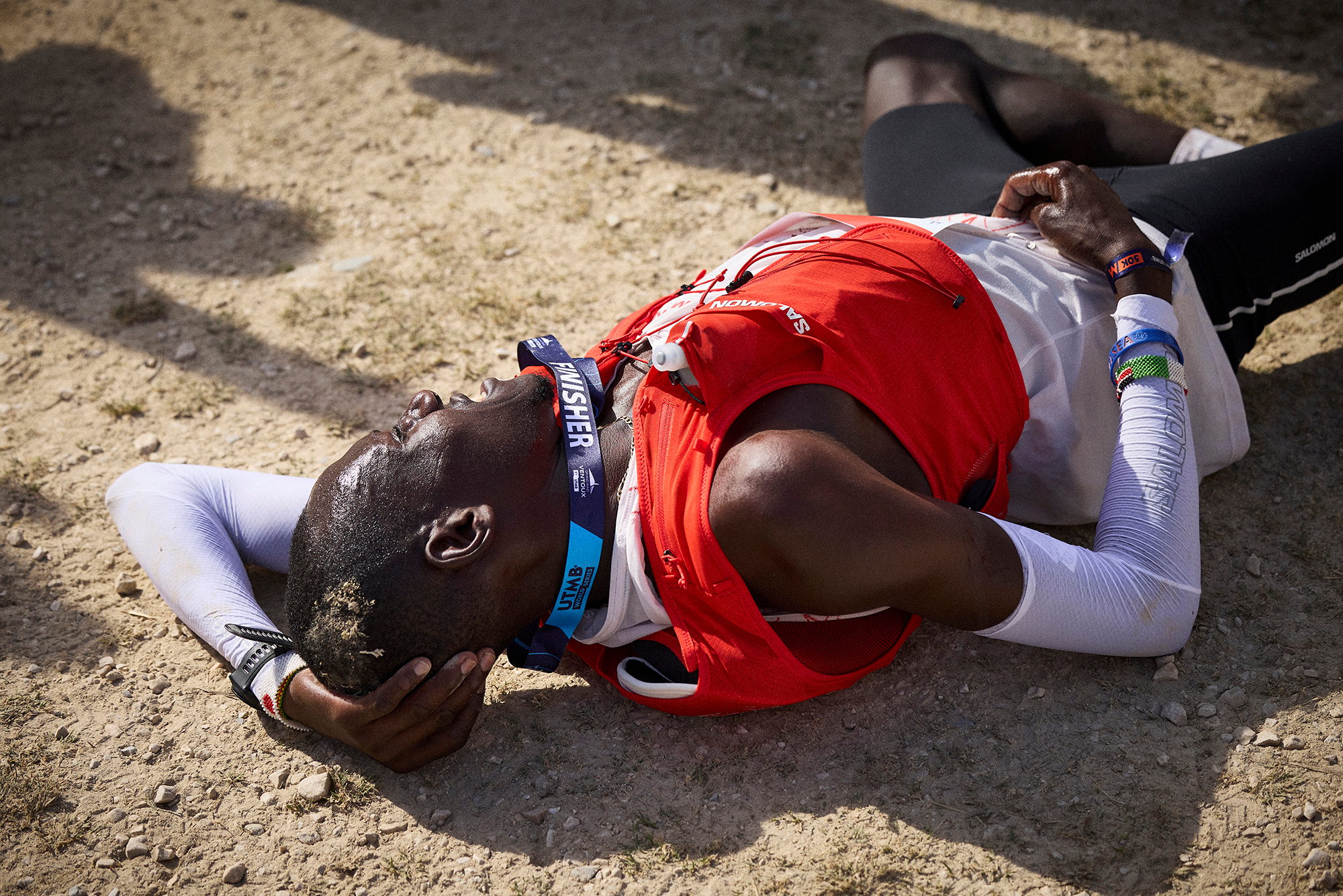 Coureur effondré dans la poussière, mains derrière la tête