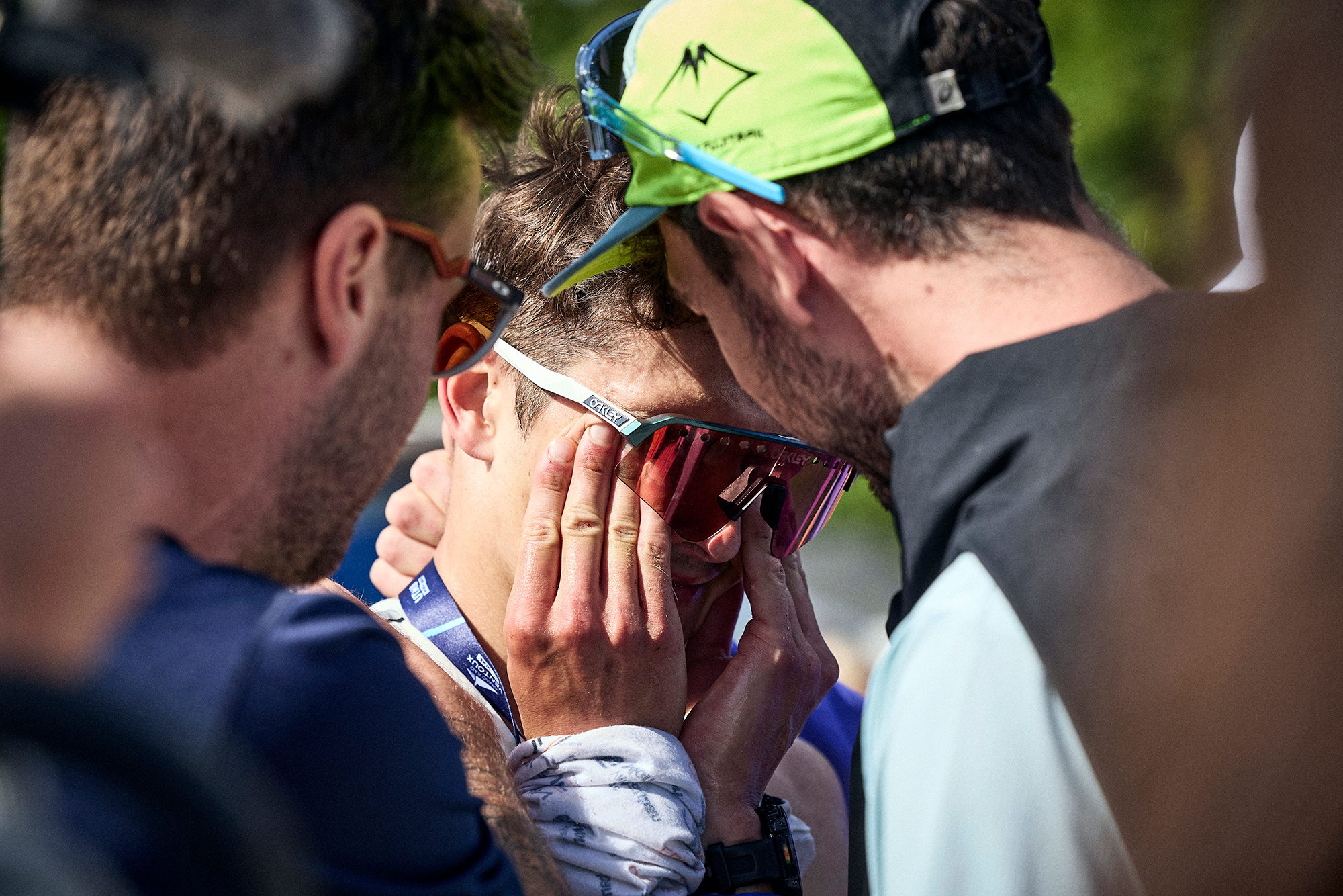 Coureur en larmes, mains sur le visage, entouré de ses accompagnants