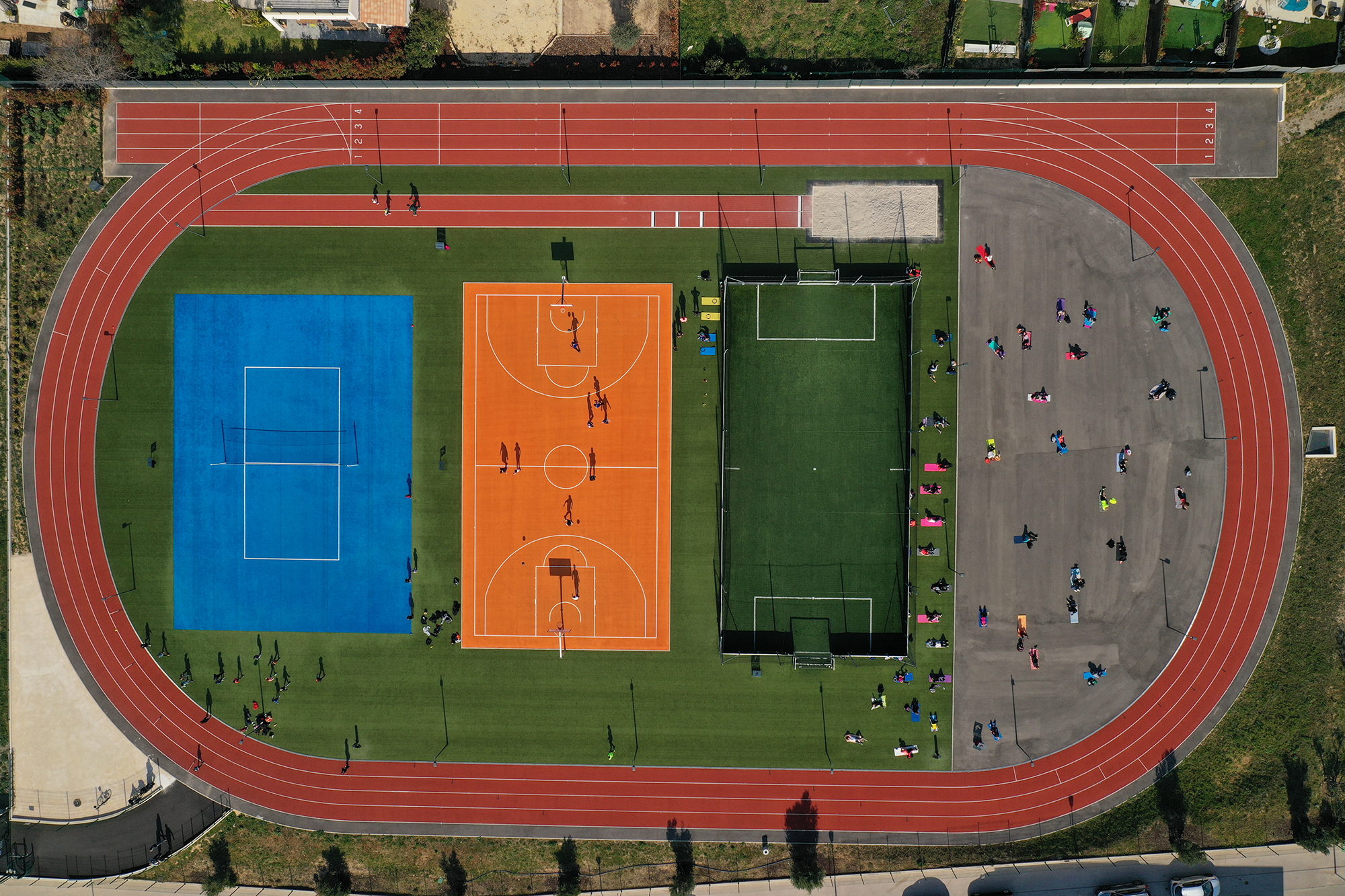 Vue aérienne d'une piste d'athlétisme entourant des terrains de sport colorés