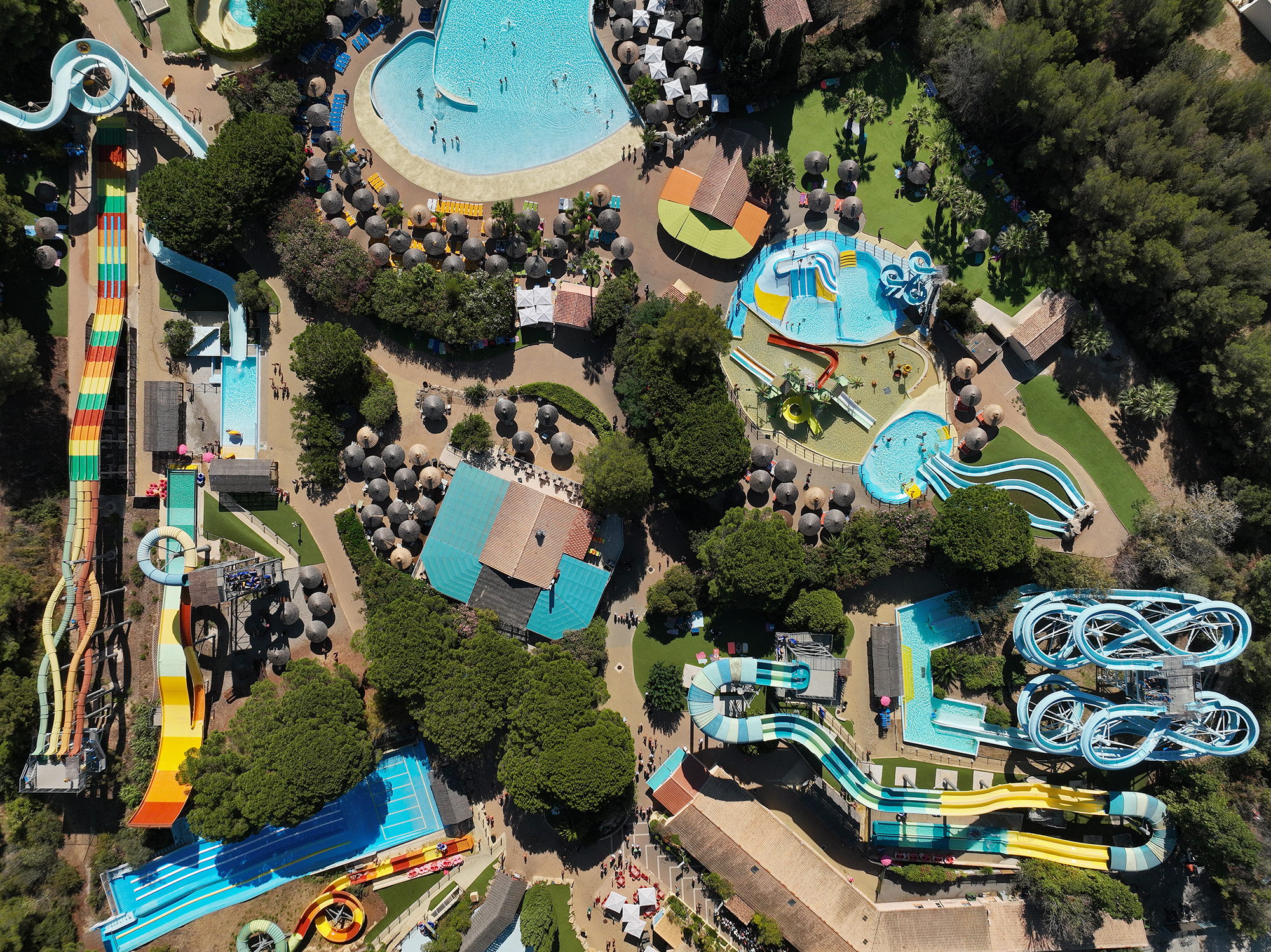 Vue aérienne d'un parc aquatique, toboggans et bassins au milieu des pins